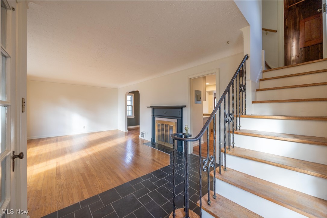 3797 Northwood Road Cleveland, OH 44118 - Photo 22 of 49 Staircase with a fireplace with flush hearth, arched walkways, and wood finished floors