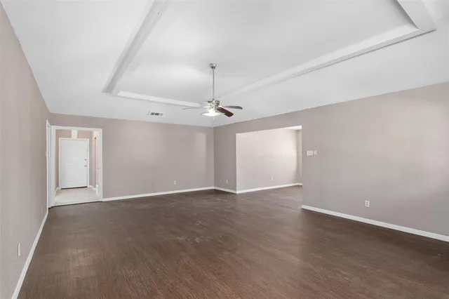 an empty room with wooden floor ceiling fan and windows