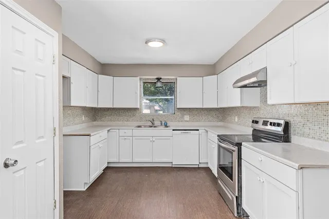 a kitchen with stainless steel appliances granite countertop white cabinets stove a sink and dishwasher