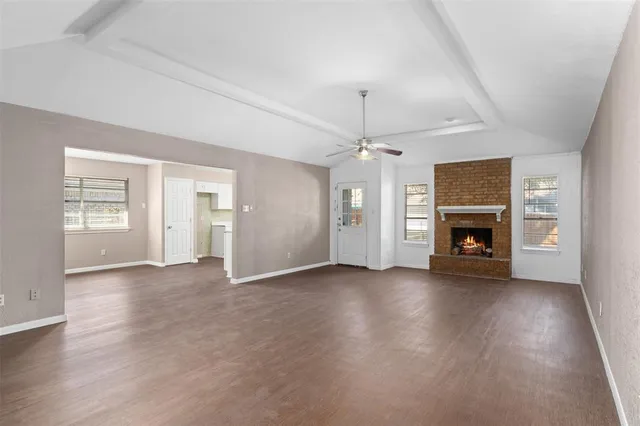 an empty room with wooden floor fireplace and cabinet