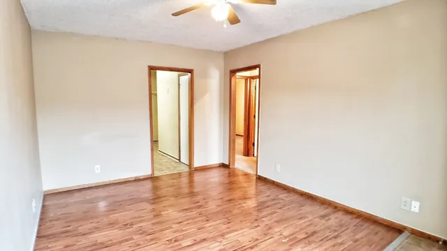 a view of an empty room with wooden floor and a window