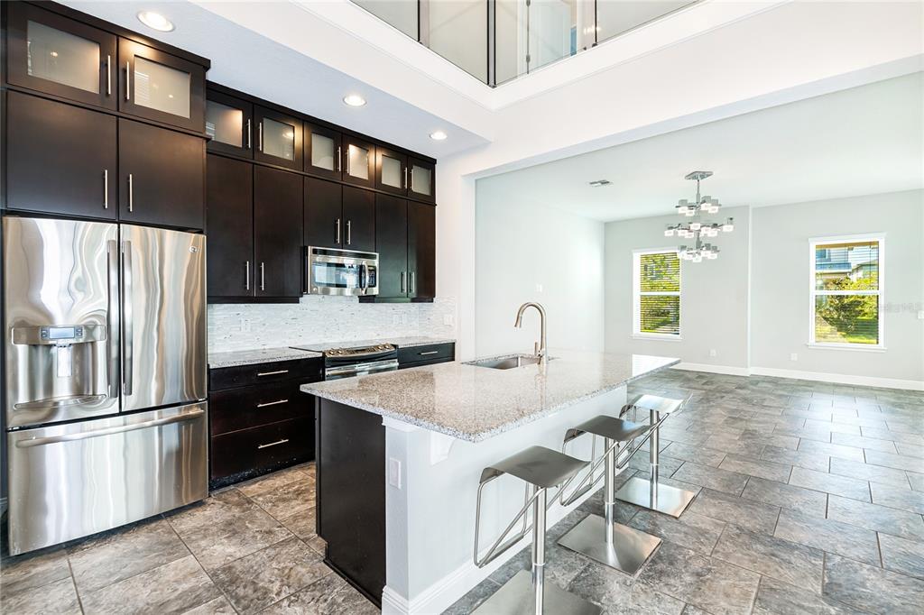 8555 Pinter Street Orlando, FL 32827 - Photo 3 of 32 a kitchen with stainless steel appliances granite countertop a sink stove and refrigerator