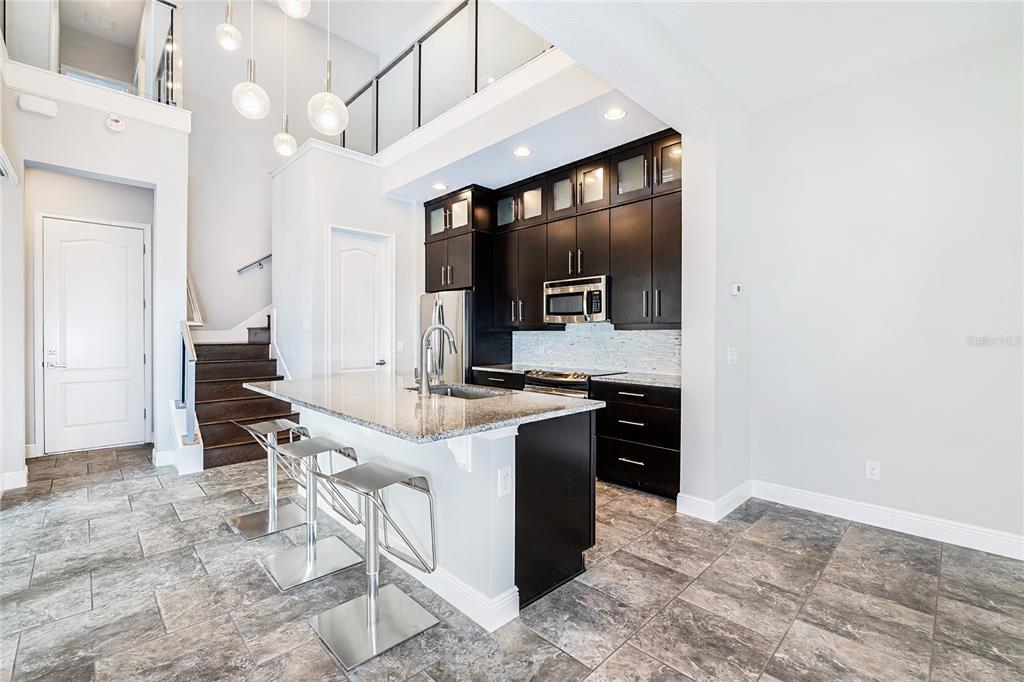 8555 Pinter Street Orlando, FL 32827 - Photo 9 of 32 a kitchen with stainless steel appliances kitchen island granite countertop a stove and a sink