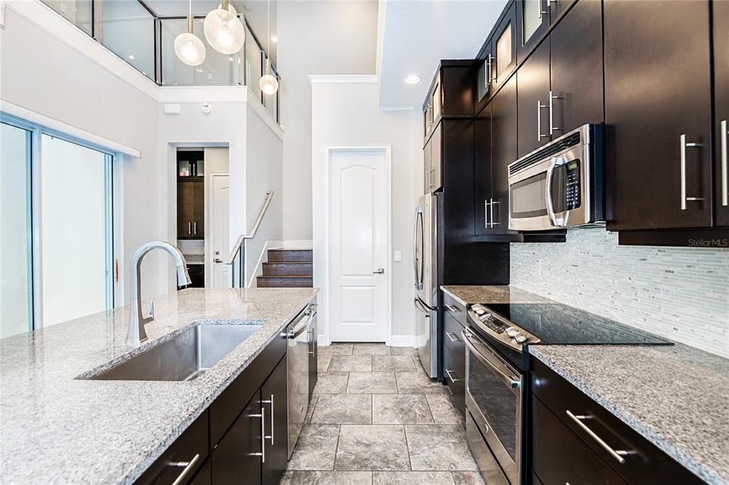 8555 Pinter Street Orlando, FL 32827 - Photo 10 of 32 a kitchen with stainless steel appliances granite countertop a sink a stove and a refrigerator