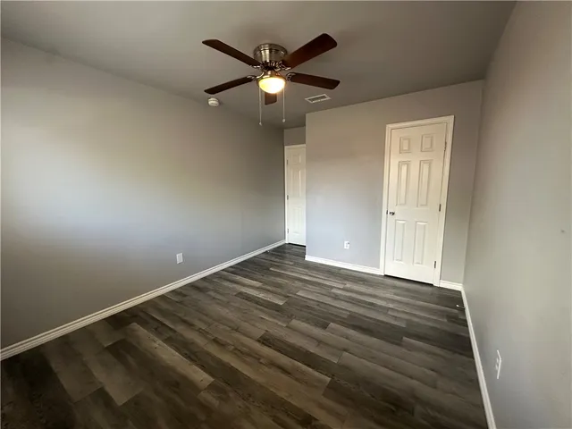 an empty room with wooden floor and a ceiling fan