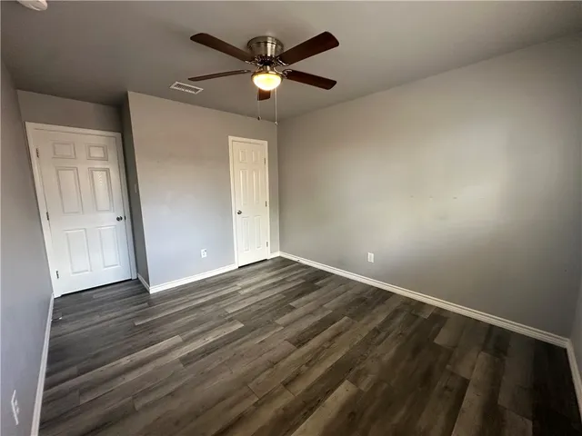 an empty room with wooden floor chandelier and windows