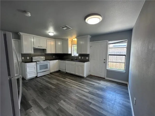 a kitchen with granite countertop a stove a sink and a refrigerator