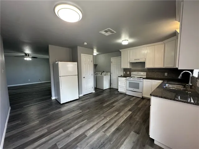 a kitchen with a refrigerator a stove top oven and white cabinets