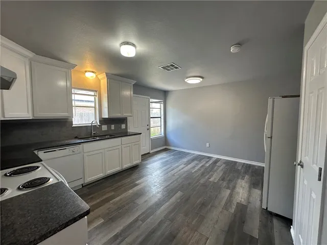 a kitchen with granite countertop a stove a sink and a refrigerator