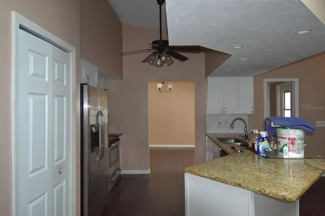a kitchen with a table chairs refrigerator and wooden floor
