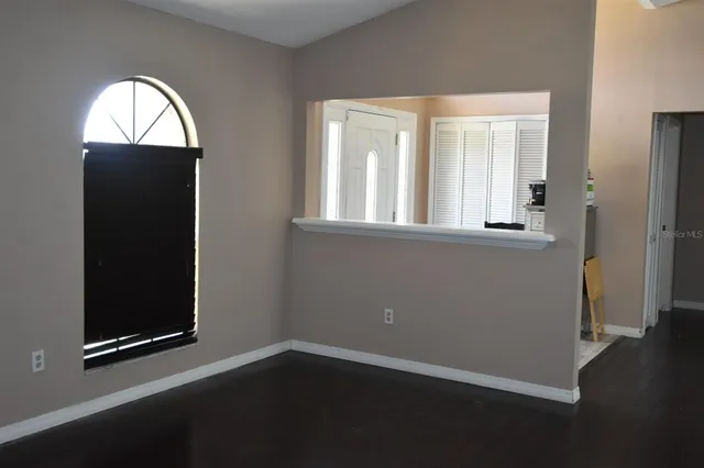 an empty room with wooden floor closet and windows