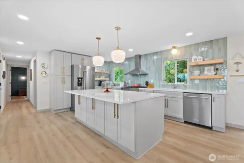 a kitchen with kitchen island granite countertop a sink a counter top space stainless steel appliances and cabinets