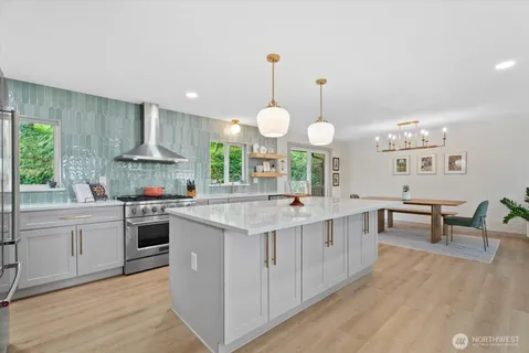 a kitchen with kitchen island granite countertop a sink a stove and a wooden floors