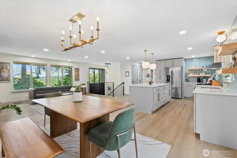 a open kitchen with kitchen island a stove a table and chairs in it