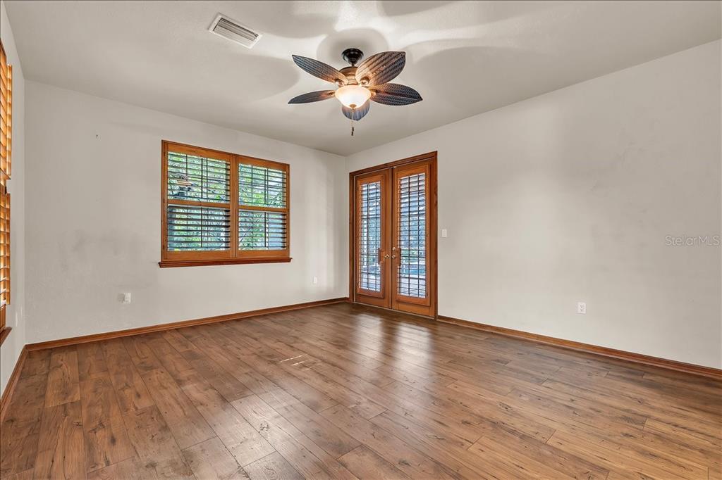 10597 Southwest Kissimmee Road Arcadia, FL 34269 - Photo 20 of 54 an empty room with wooden floor chandelier fan and windows