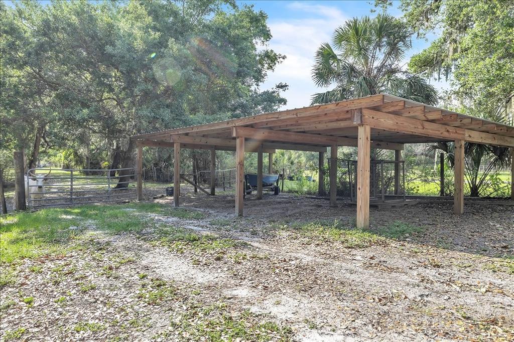 10597 Southwest Kissimmee Road Arcadia, FL 34269 - Photo 50 of 54 a view of a barn with a table and chairs under an umbrella