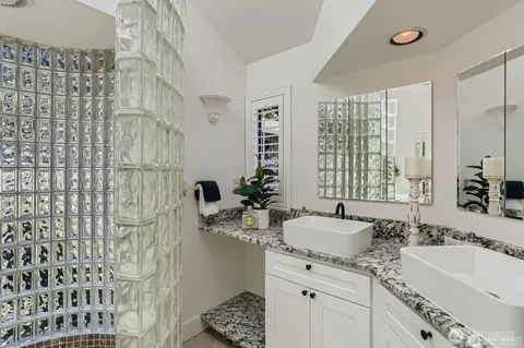 a bathroom with a double vanity sink mirror and shower