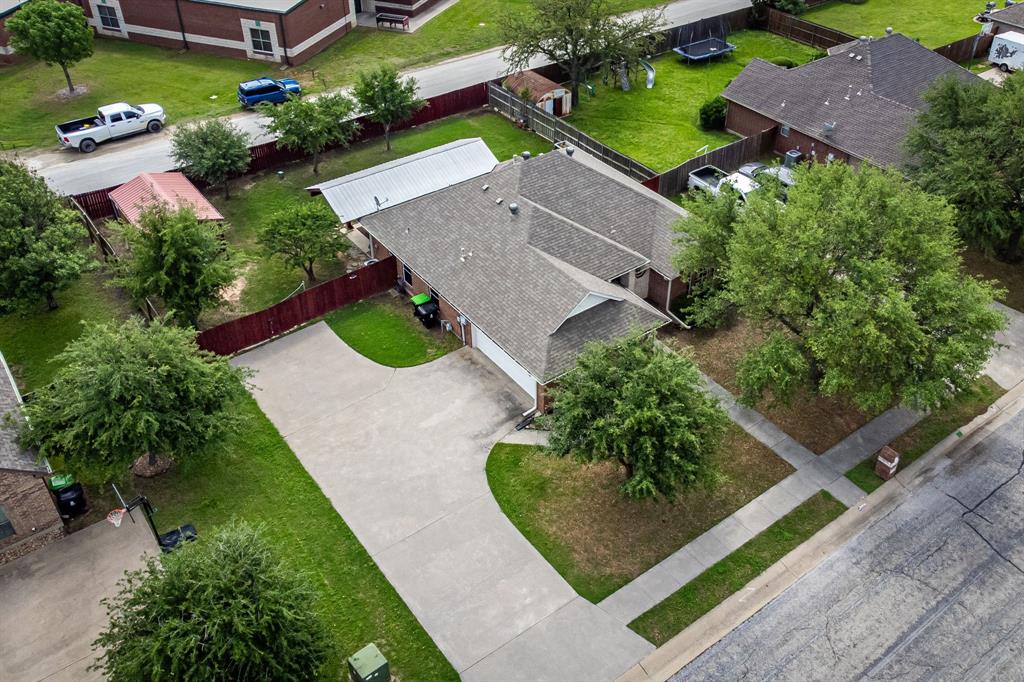 1401 Hickory Drive Pilot Point, TX 76258 - Photo 10 of 34 Aerial view of a residential property featuring a gray shingle roof, a concrete driveway, and mature landscaping