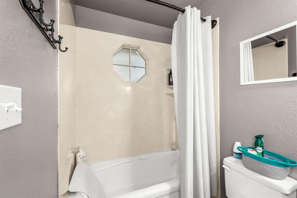 1401 Hickory Drive Pilot Point, TX 76258 - Photo 11 of 34 Bathtub shower combination featuring an octagonal window, built-in shelving, and a white shower curtain
