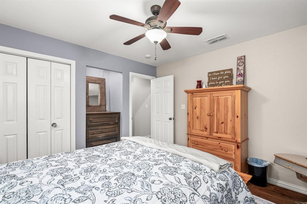 1401 Hickory Drive Pilot Point, TX 76258 - Photo 16 of 34 Bedroom featuring a ceiling fan with integrated lighting, wood-finish flooring, white bi-fold closet doors, and light-toned walls