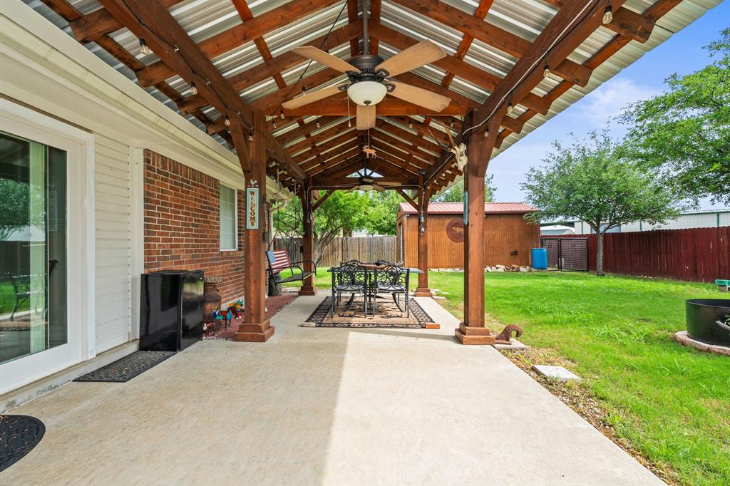 1401 Hickory Drive Pilot Point, TX 76258 - Photo 21 of 34 Expansive covered patio featuring a wood beam and metal roof structure, ceiling fan, and string lights