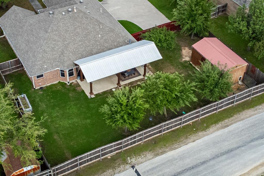 1401 Hickory Drive Pilot Point, TX 76258 - Photo 30 of 34 Expansive backyard featuring a covered patio with a metal roof, a detached shed with a red metal roof, and a wood privacy fence