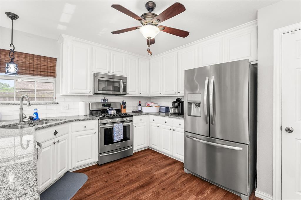 1401 Hickory Drive Pilot Point, TX 76258 - Photo 6 of 34 Kitchen featuring white cabinetry, granite countertops, stainless steel appliances, wood-finish flooring, and a white subway tile backsplash