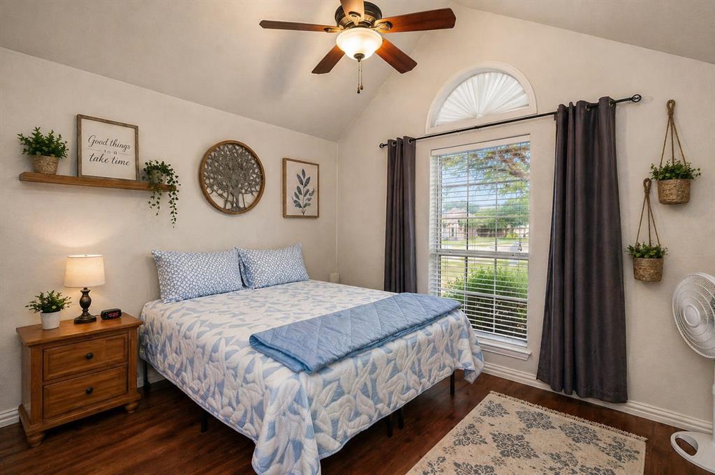 1401 Hickory Drive Pilot Point, TX 76258 - Photo 7 of 34 Spacious bedroom featuring vaulted ceilings, wood-finish flooring, a ceiling fan with integrated lighting, and a large window with an arched transom