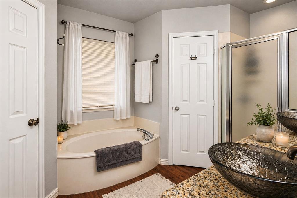 1401 Hickory Drive Pilot Point, TX 76258 - Photo 8 of 34 Bathroom featuring a built-in corner soaking tub with a window above, wood-finish flooring, a glass-enclosed shower, and a vanity with granite-style countertop and vessel sink