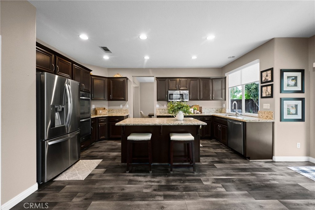 7220 Cumberland Place Rancho Cucamonga, CA 91739 - Photo 11 of 41 Chef-inspired kitchen featuring espresso cabinetry, granite countertops, stainless steel appliances, and a large center island.