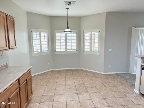 a view of an empty room with window and chandelier fan