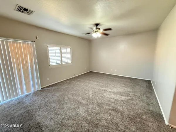 an empty room with windows and fan chandelier
