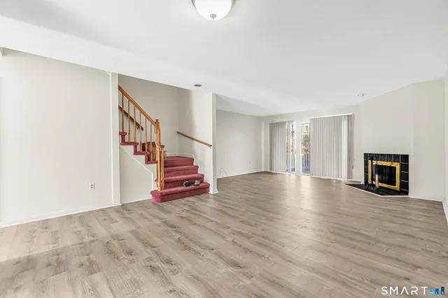 a view of an empty room with wooden floor and stairs