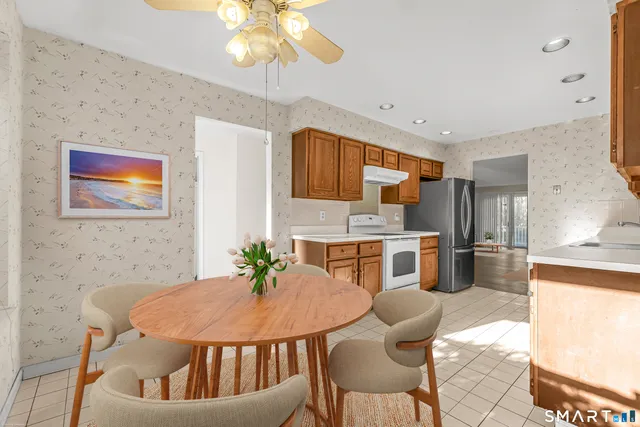 a kitchen with stainless steel appliances kitchen island granite countertop a sink a refrigerator a stove a dining table and chairs with wooden floor