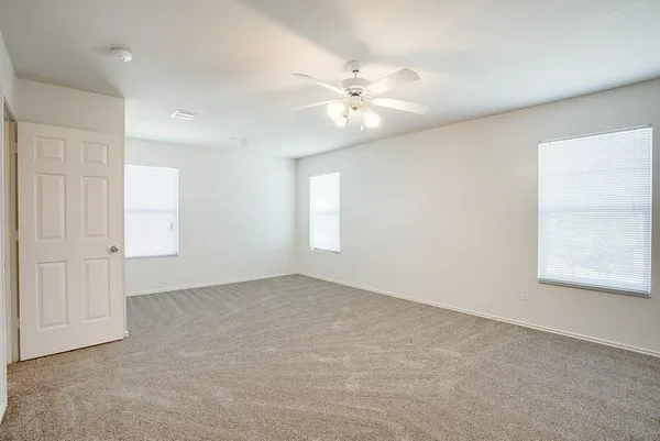 an empty room with windows and fan
