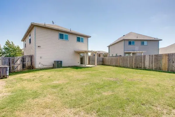 a view of a house with backyard and wooden fence