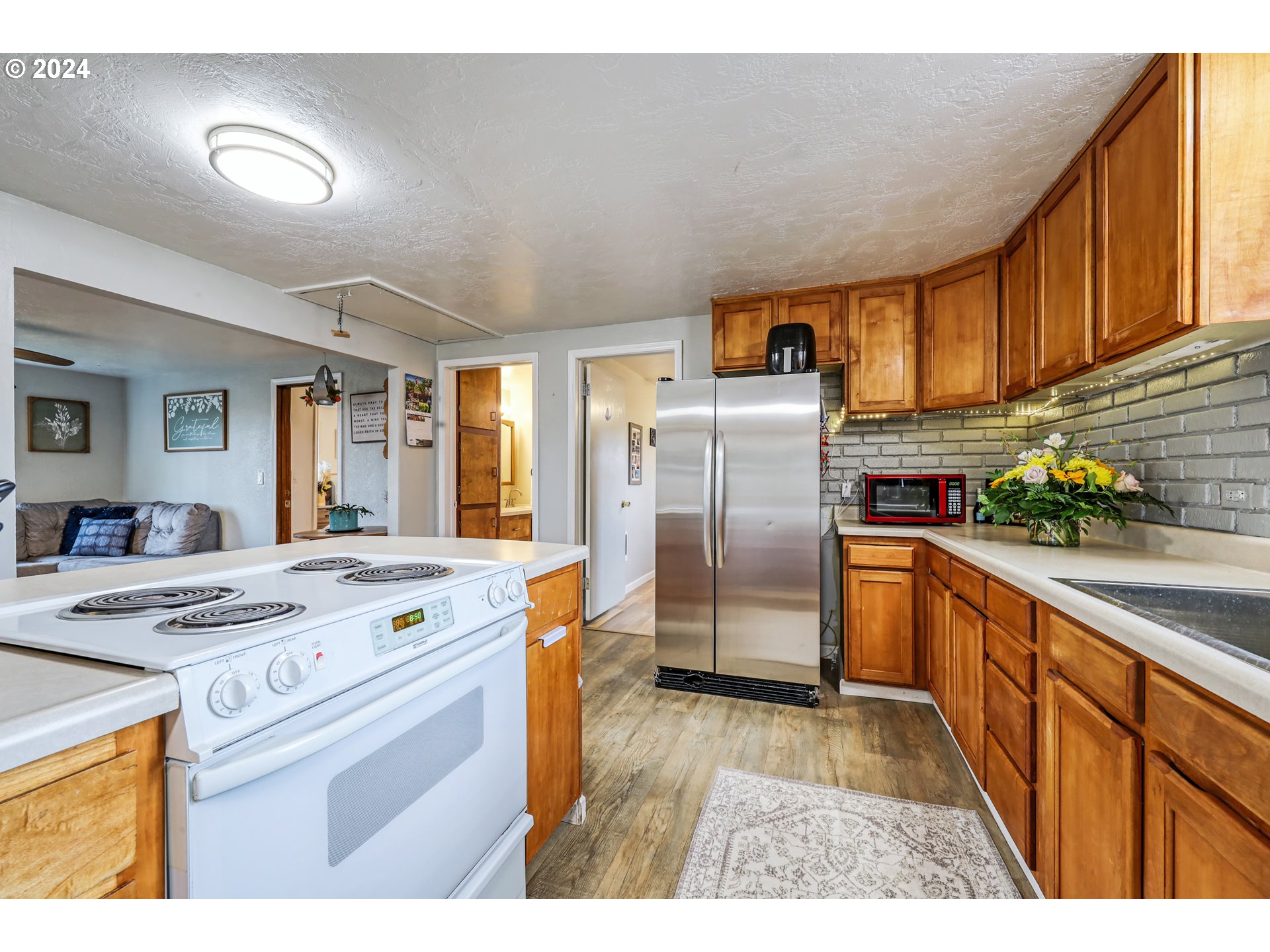 615 48th Street Springfield, OR 97478 - Photo 8 of 16 a kitchen with stainless steel appliances granite countertop a refrigerator a stove a sink dishwasher and white cabinets with wooden floor