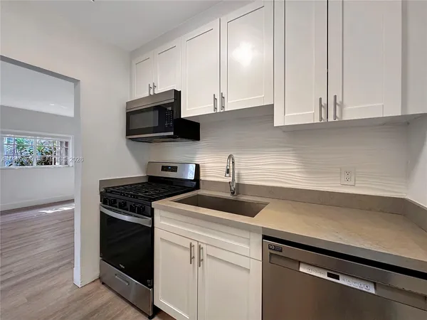 a kitchen with granite countertop white cabinets and a stove