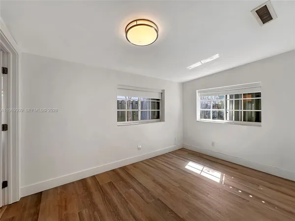 a view of empty room with wooden floor and window