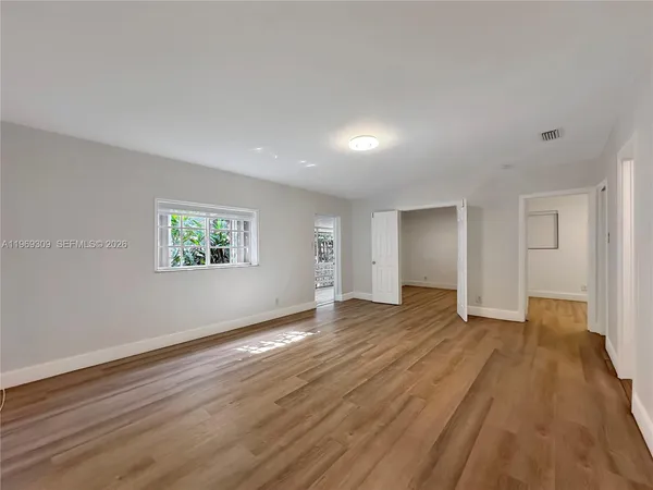 an empty room with wooden floor and windows