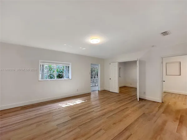 a view of an empty room with wooden floor and closet