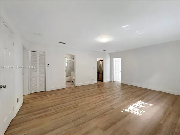 a view of an empty room with wooden floor and a window