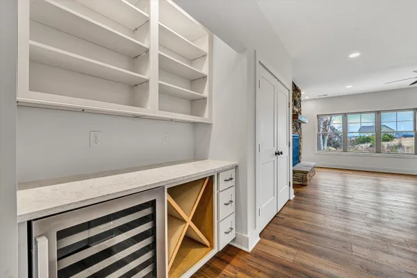 an empty room with wooden floor fan and windows