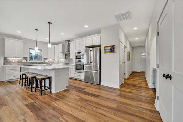 a living room with furniture wooden floor and a kitchen view