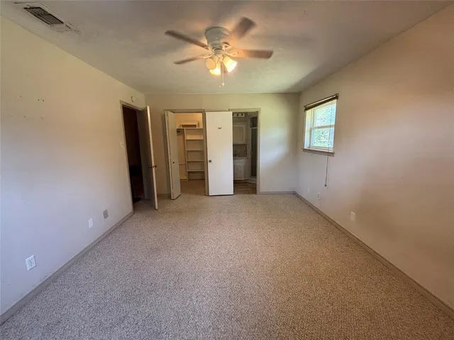 an empty room with closet and a ceiling fan