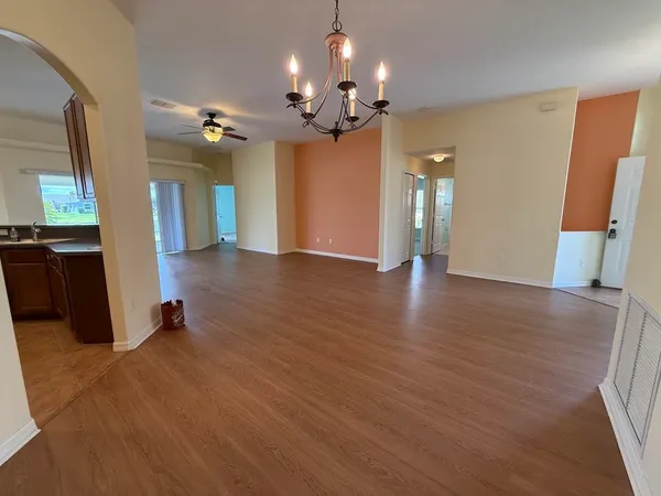 a view of an empty room with wooden floor and a ceiling fan
