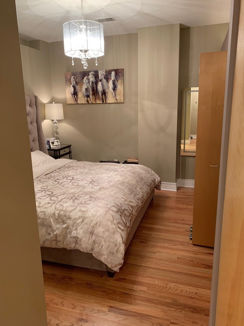 212 West Washington Street, Unit 1106 Chicago, IL 60606 - Photo 20 of 25 a bedroom with a bed and dresser with wooden floor