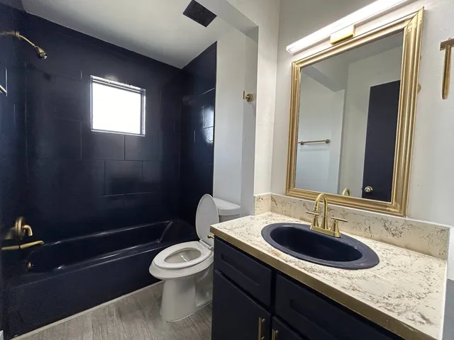 a bathroom with a granite countertop toilet a sink and a mirror