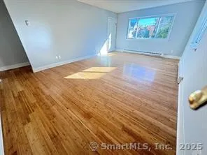 a view of empty room with window and wooden floor