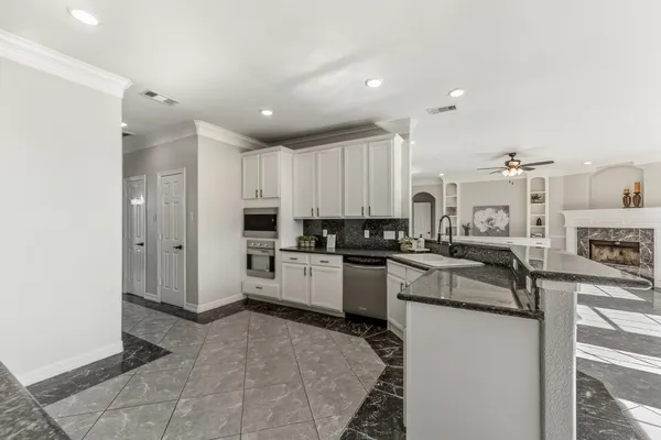 a large kitchen with granite countertop a large counter top stainless steel appliances and cabinets